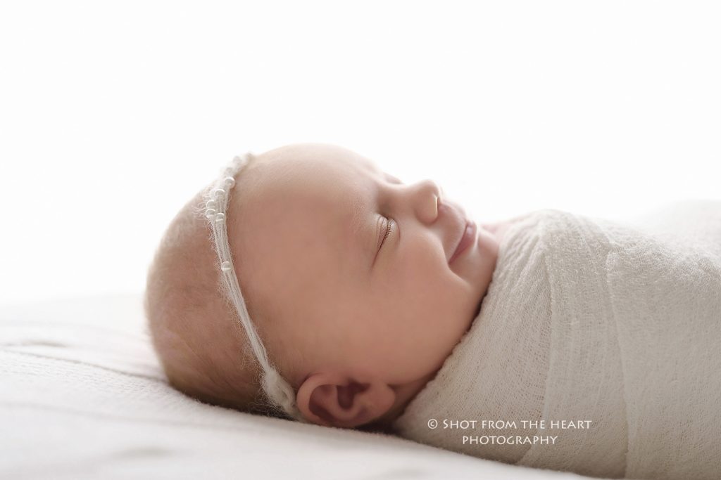 newborn baby on white background smiling photography