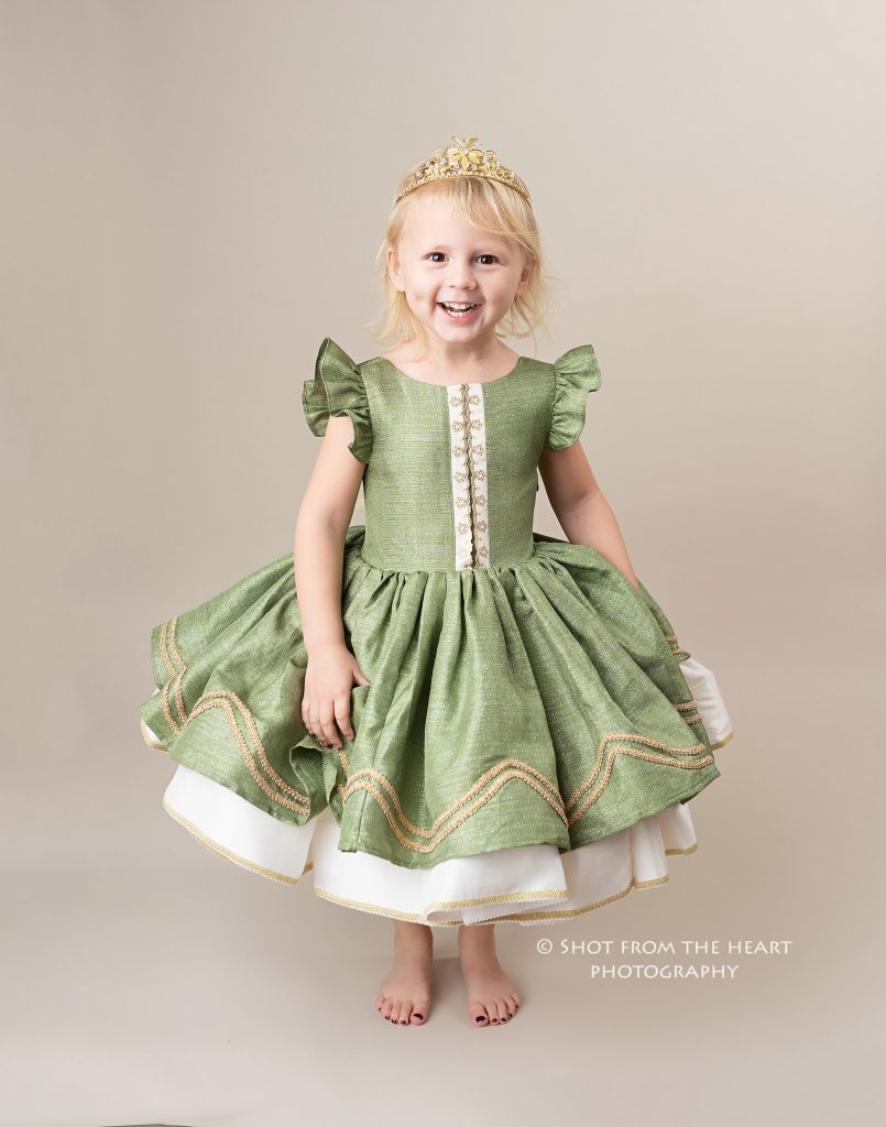 little girl in green gleam in the light dollcake dress with tan background, atlanta Georgia child photographer