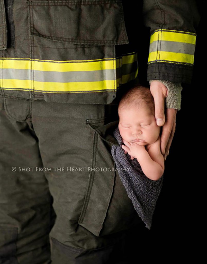newborn baby inside dads pocket of firefighter turnout gear