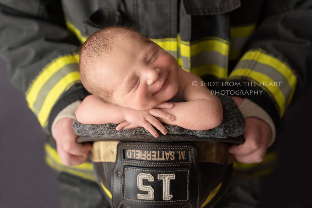 newborn baby photography with firefighter turnout bunker gear. Baby inside firefighter helmet. 