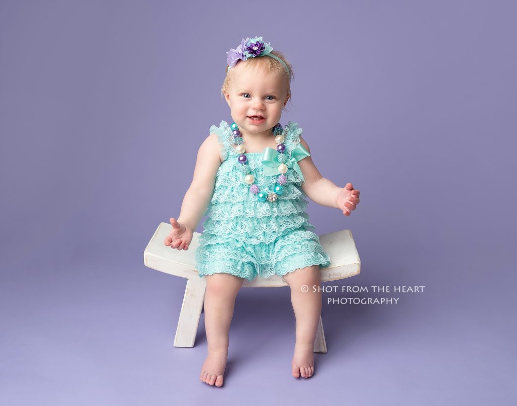 first birthday photo session, baby girl wearing aqua teal romper with purple background, canton ga baby photographer