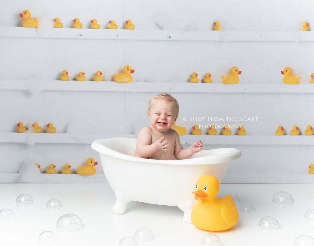 Bubble bath with rubber ducky as part of a photo session after a first birthday cake smash.