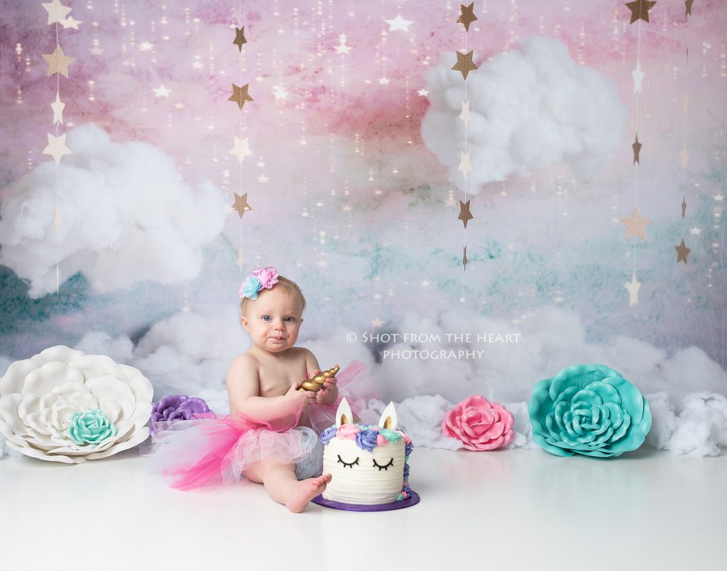 Unicorn birthday cake smash photography session with pink, purple, teal, and white colors. 