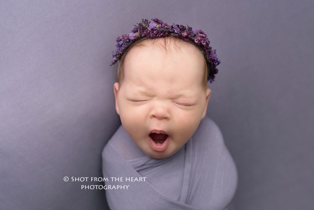 newborn baby yawning photography with purple background Alpharetta