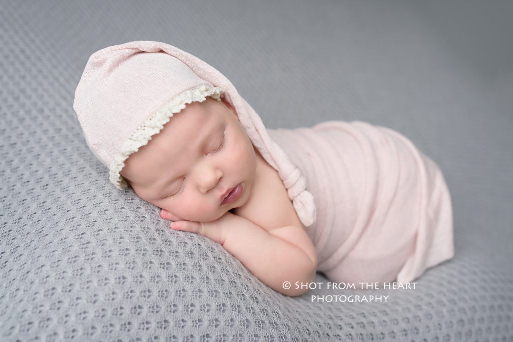 newborn baby sleeping with gray background, pink wrap, pink sleeping hat, Alpharetta Georgia newborn and maternity photographer