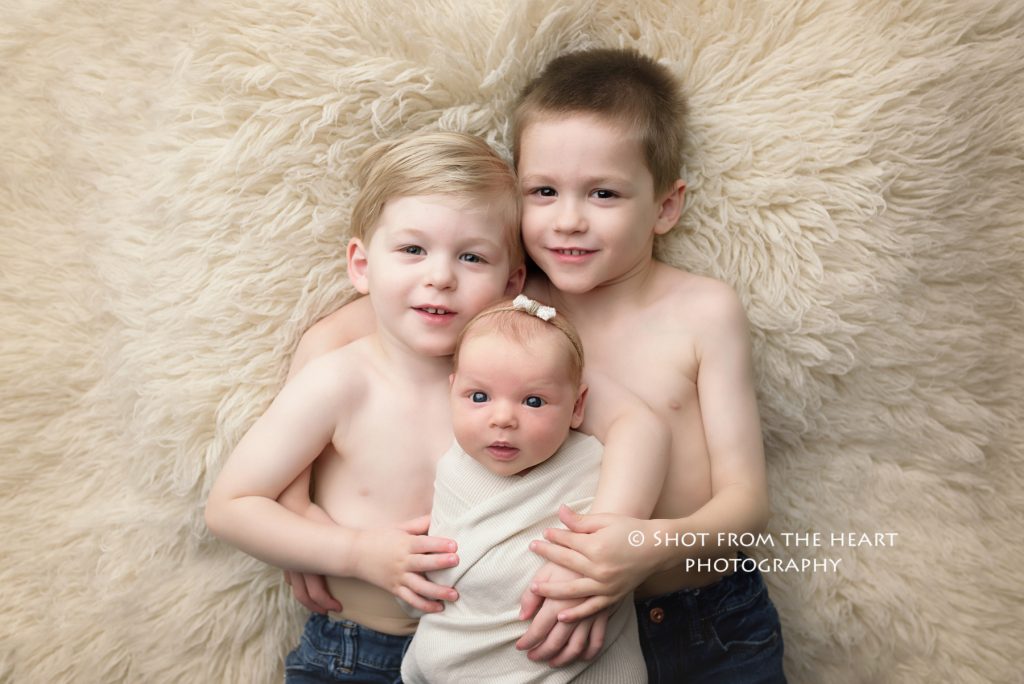 Two brothers holding newborn baby sister professional photographer canton Georgia 