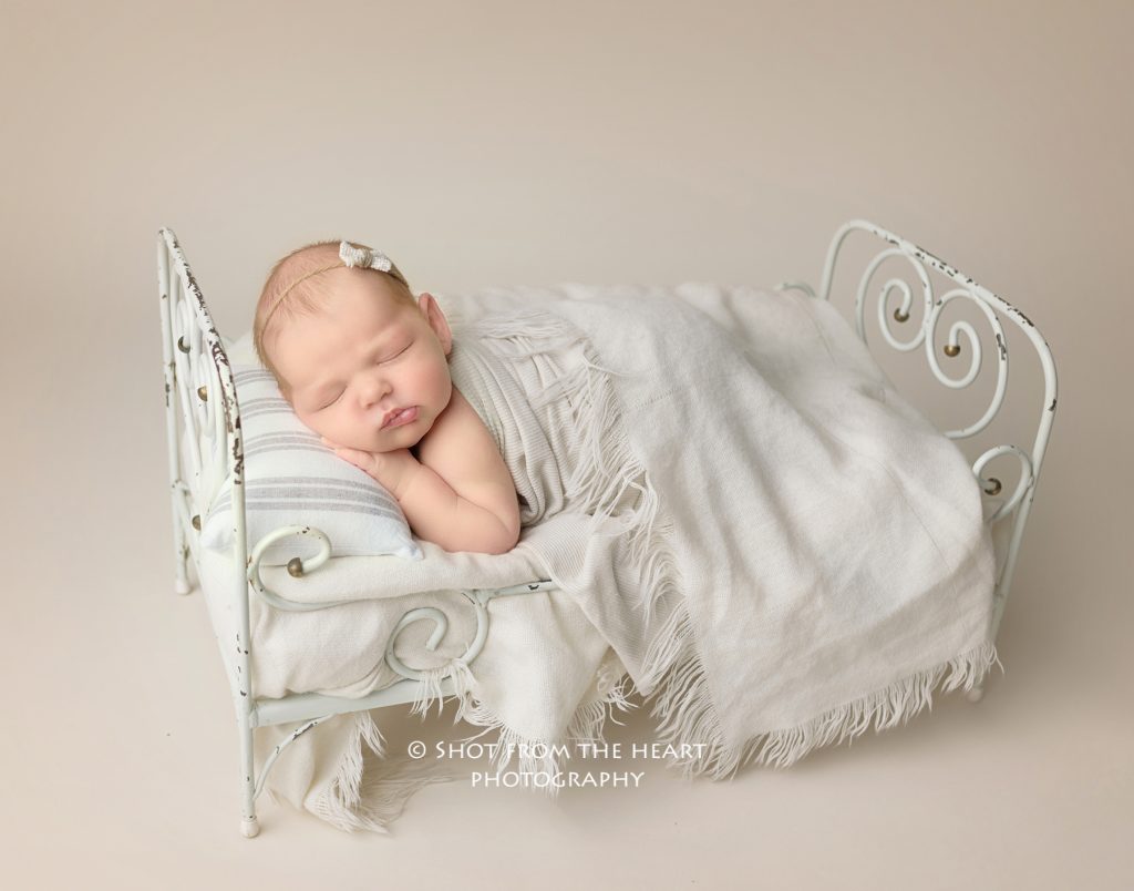 Newborn baby girl in tiny bed, professional newborn photographer Alpharetta Georgia