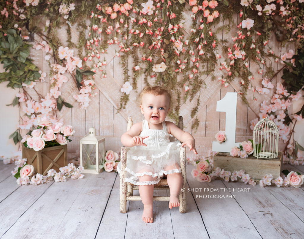First birthday, girl in white, rustic floral backdrop