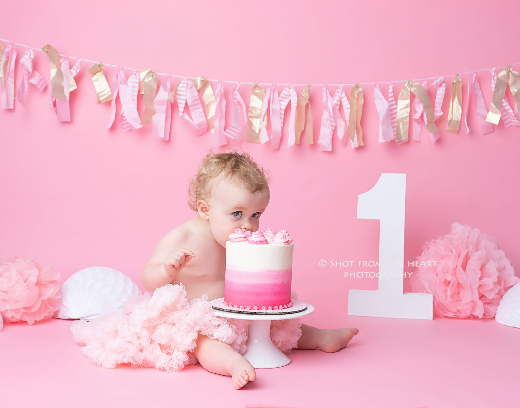 First birthday girl pink backdrop cake smash baby face planting cake