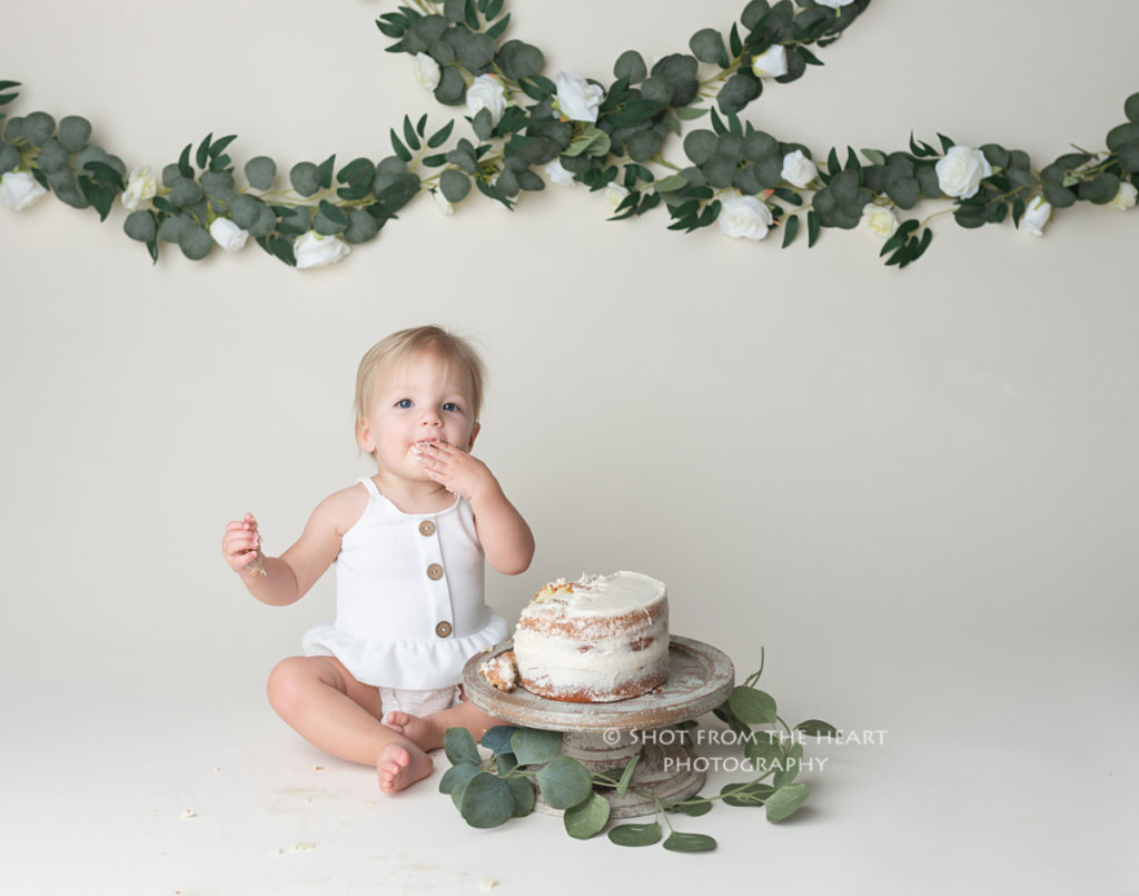 rustic neutral 1st birthday cake smash photography session with vines and greenery
